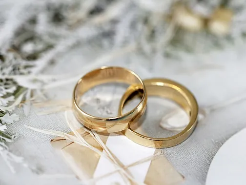Zwei goldene Eheringe liegen auf einem weißen Untergrund.